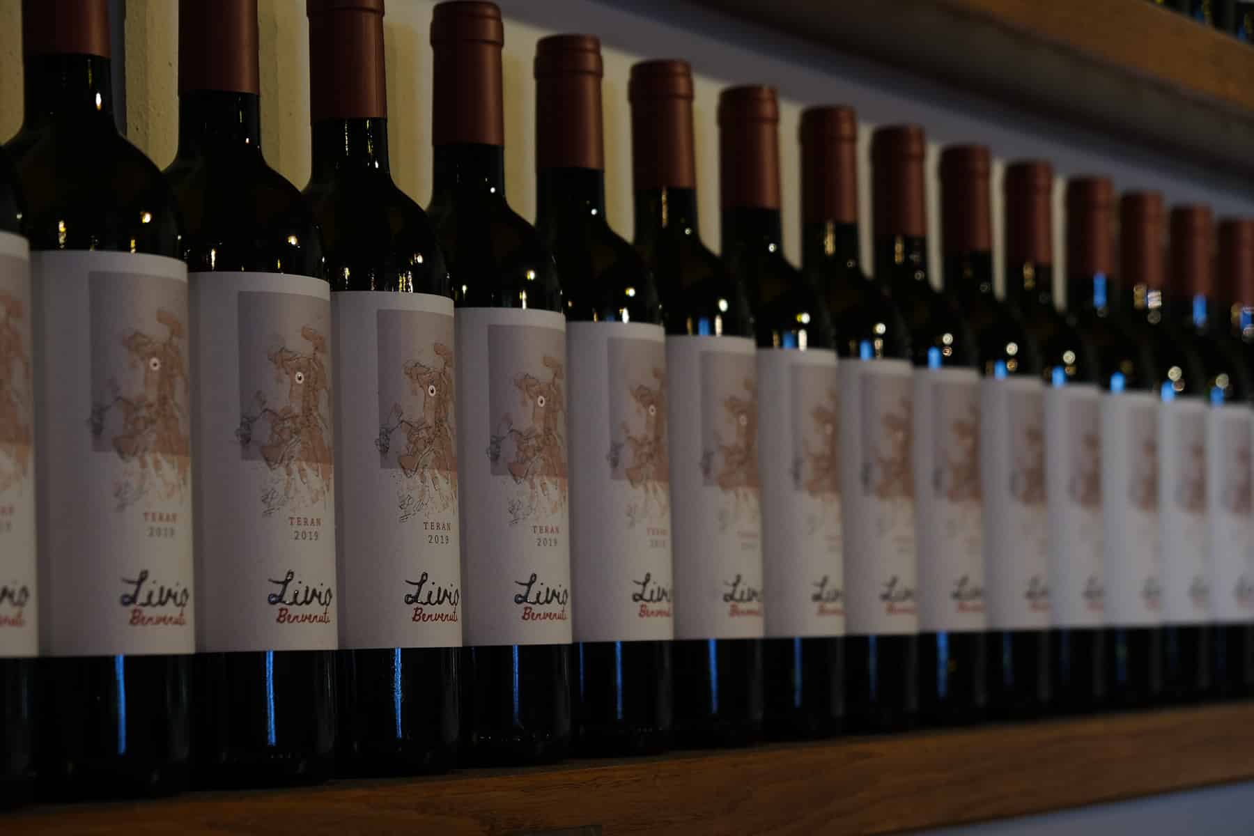 A row of wine bottles lined up on a shelf in Istria.